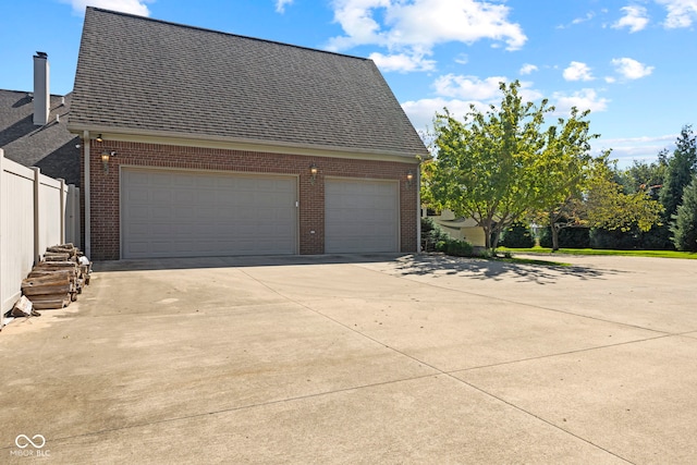 view of side of home featuring a garage, brick siding, a shingled roof, and driveway