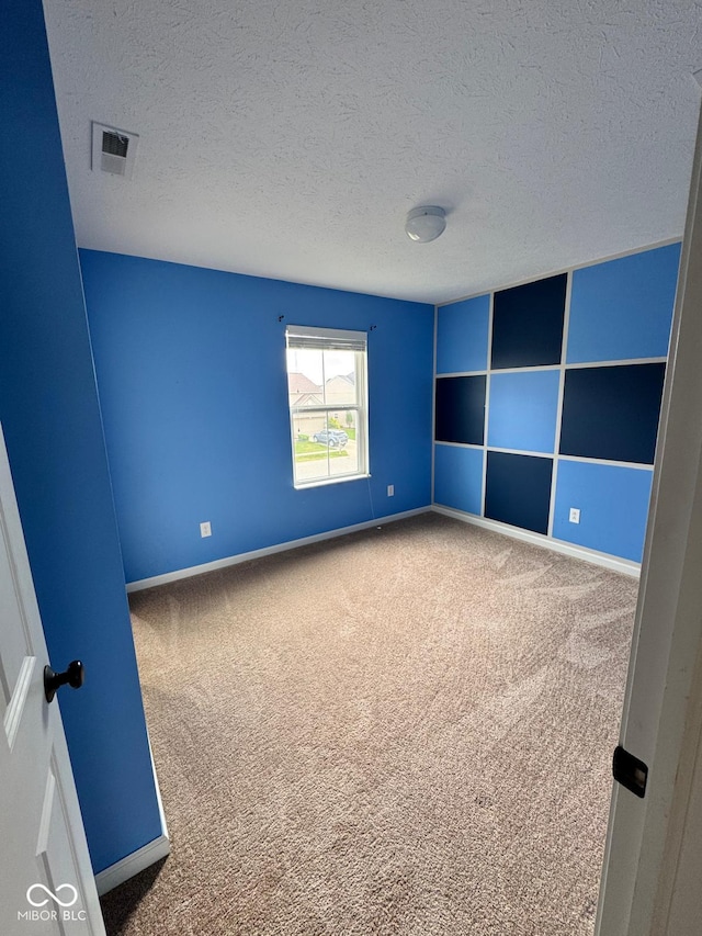 carpeted empty room featuring a textured ceiling