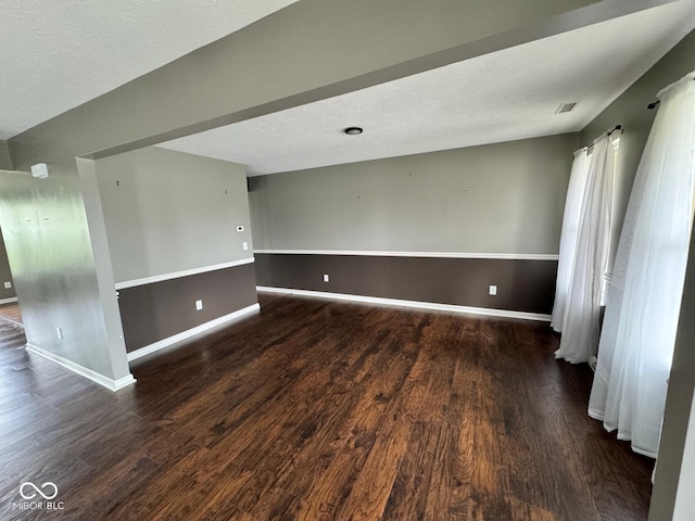 spare room featuring dark wood-type flooring and a textured ceiling