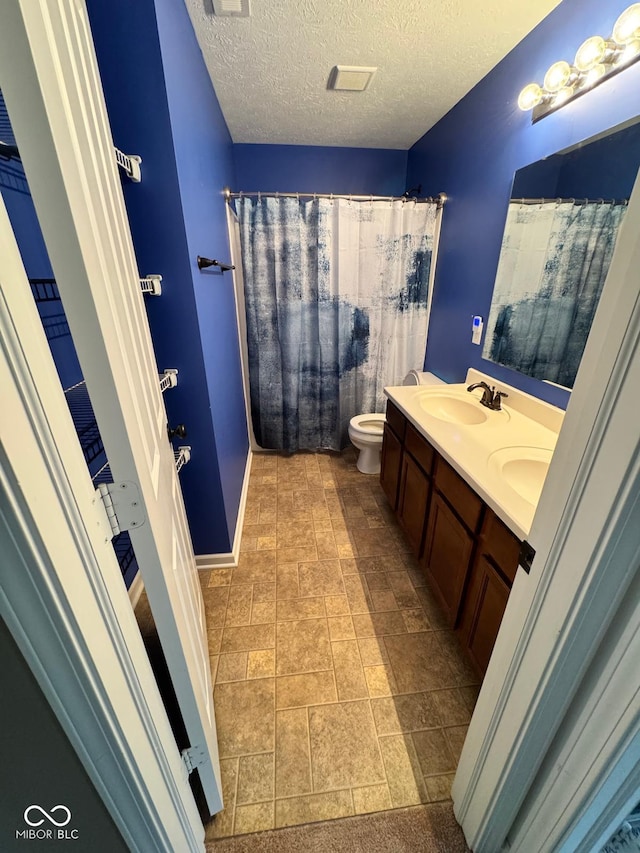 bathroom with a textured ceiling, vanity, and toilet