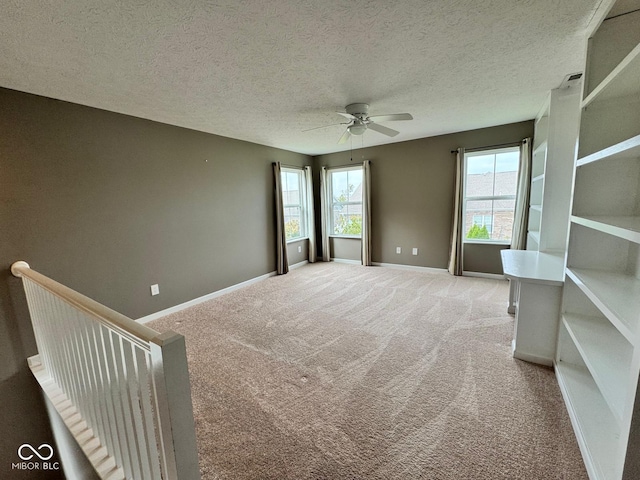 unfurnished room featuring a textured ceiling, ceiling fan, and light colored carpet