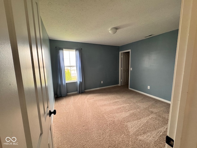 unfurnished room with a textured ceiling and light colored carpet