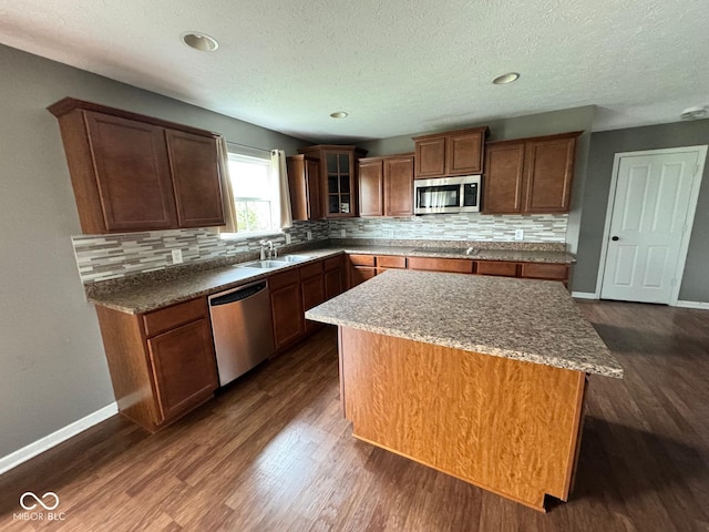 kitchen with a textured ceiling, backsplash, stainless steel appliances, a center island, and dark hardwood / wood-style flooring