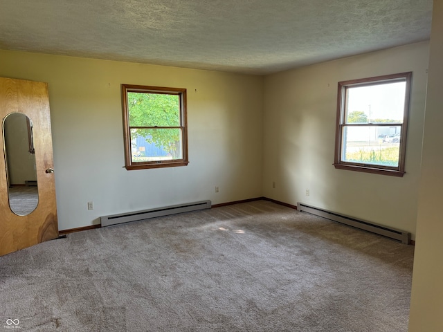 carpeted spare room featuring a baseboard heating unit and a textured ceiling