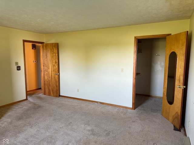 unfurnished bedroom featuring a textured ceiling, light carpet, and a spacious closet