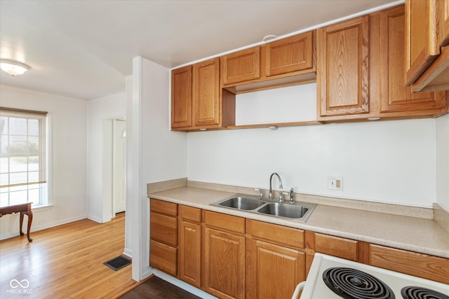 kitchen featuring white range, light hardwood / wood-style floors, and sink