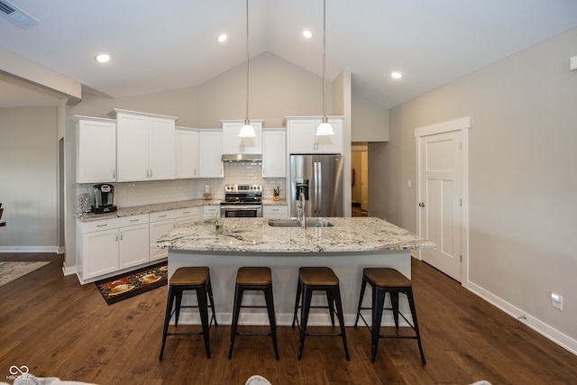 kitchen featuring pendant lighting, white cabinetry, stainless steel appliances, dark wood-type flooring, and a center island with sink