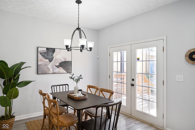 dining room with french doors, light hardwood / wood-style floors, a textured ceiling, and a chandelier