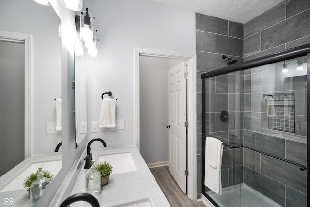 bathroom featuring a shower with door, wood-type flooring, a textured ceiling, and vanity