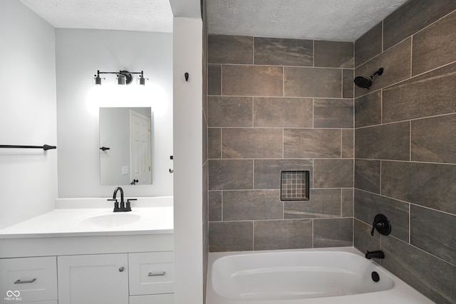 bathroom featuring vanity, tiled shower / bath, and a textured ceiling