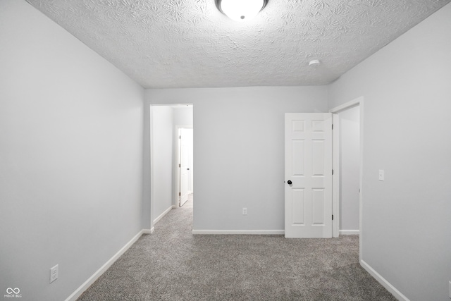 empty room featuring a textured ceiling and carpet flooring