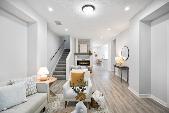 living room featuring light hardwood / wood-style flooring, a textured ceiling, and a large fireplace