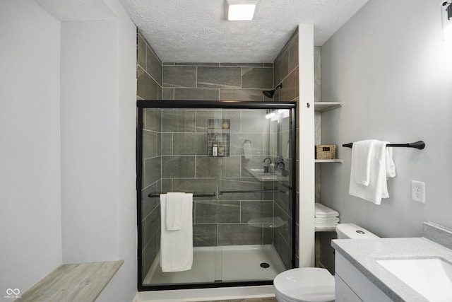 bathroom with vanity, toilet, a textured ceiling, and an enclosed shower