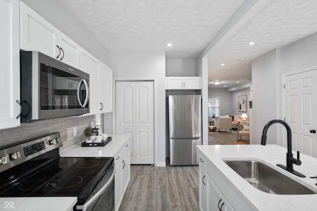 kitchen with sink, appliances with stainless steel finishes, a textured ceiling, and light wood-type flooring