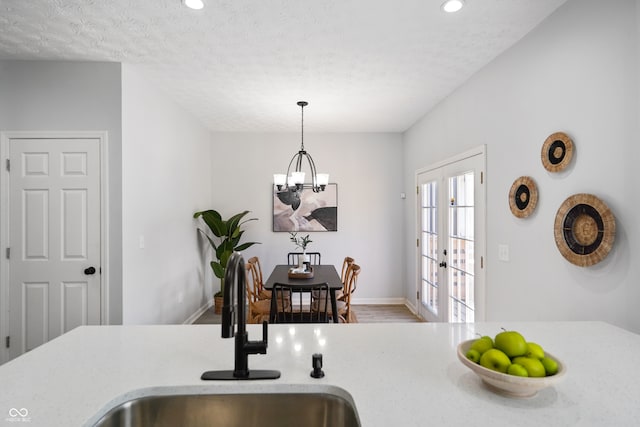 kitchen with sink, french doors, a textured ceiling, hardwood / wood-style floors, and decorative light fixtures