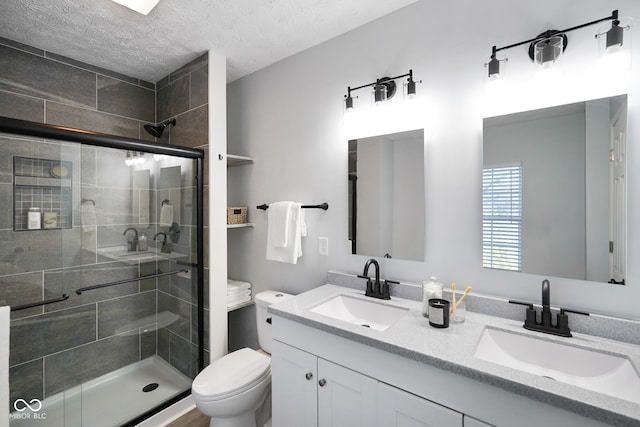 bathroom with vanity, a textured ceiling, toilet, and walk in shower