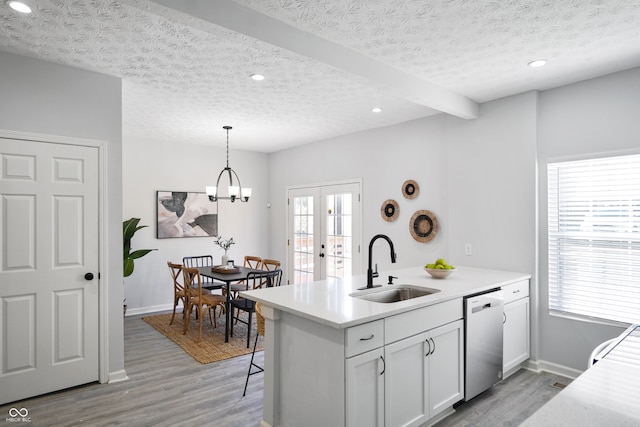 kitchen featuring white cabinets, stainless steel dishwasher, sink, and light wood-type flooring