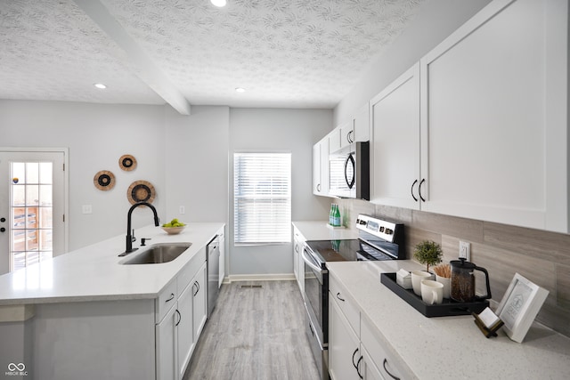 kitchen featuring appliances with stainless steel finishes, white cabinets, sink, and a textured ceiling