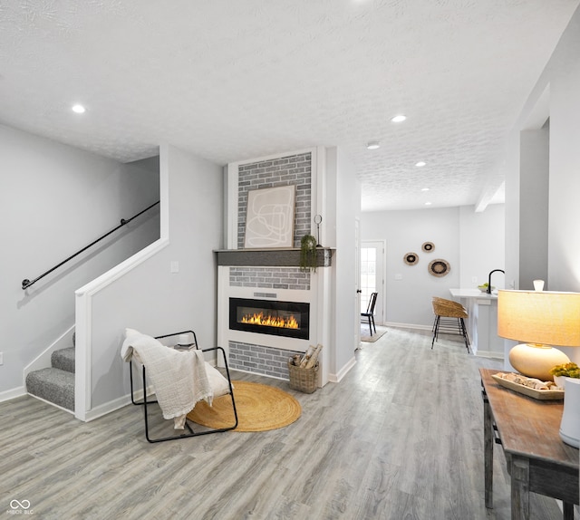 living room with light hardwood / wood-style flooring, a textured ceiling, and a fireplace