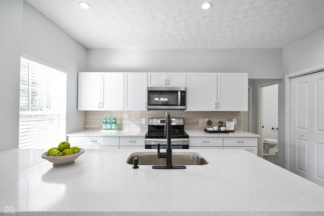 kitchen with backsplash, appliances with stainless steel finishes, a textured ceiling, and white cabinets