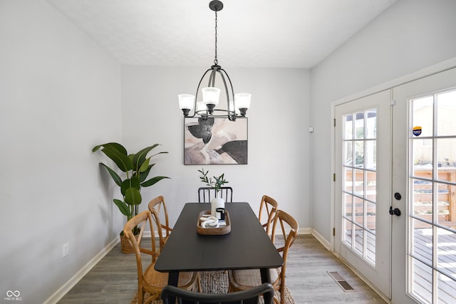 dining space featuring french doors, hardwood / wood-style flooring, and a chandelier