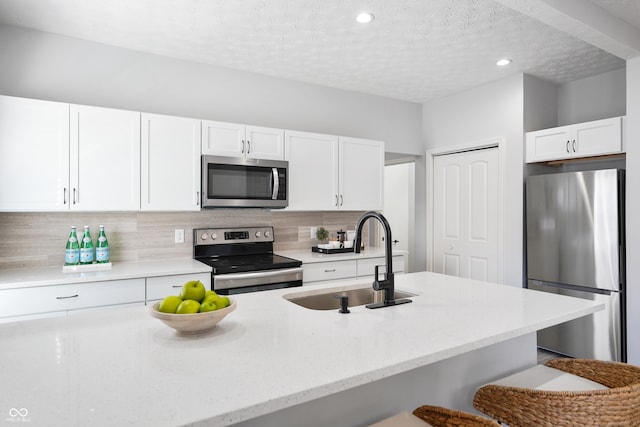 kitchen featuring decorative backsplash, a breakfast bar area, sink, white cabinets, and appliances with stainless steel finishes