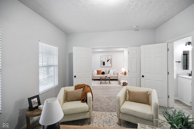 bedroom with connected bathroom, a textured ceiling, and wood-type flooring