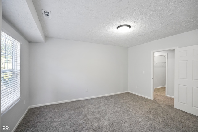 carpeted empty room featuring a textured ceiling