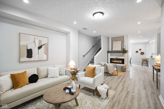 living room with light hardwood / wood-style floors, a textured ceiling, and a fireplace