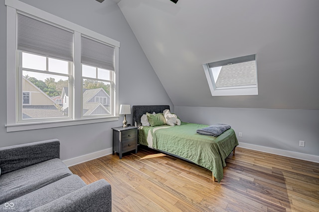 bedroom with vaulted ceiling with skylight and hardwood / wood-style floors