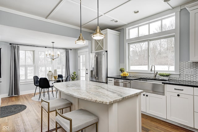 kitchen with a kitchen island, pendant lighting, white cabinetry, sink, and stainless steel appliances