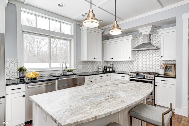 kitchen featuring sink, white cabinets, hanging light fixtures, stainless steel appliances, and wall chimney exhaust hood