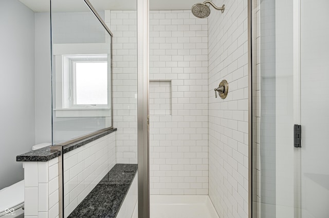 bathroom featuring a baseboard heating unit, toilet, and tiled shower