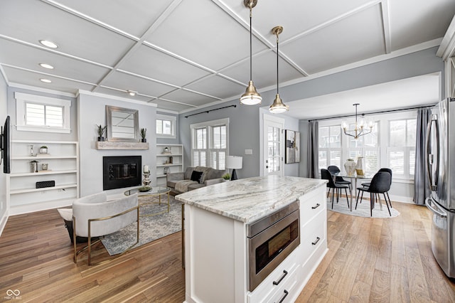 kitchen featuring white cabinets, a center island, stainless steel appliances, light stone countertops, and light hardwood / wood-style flooring