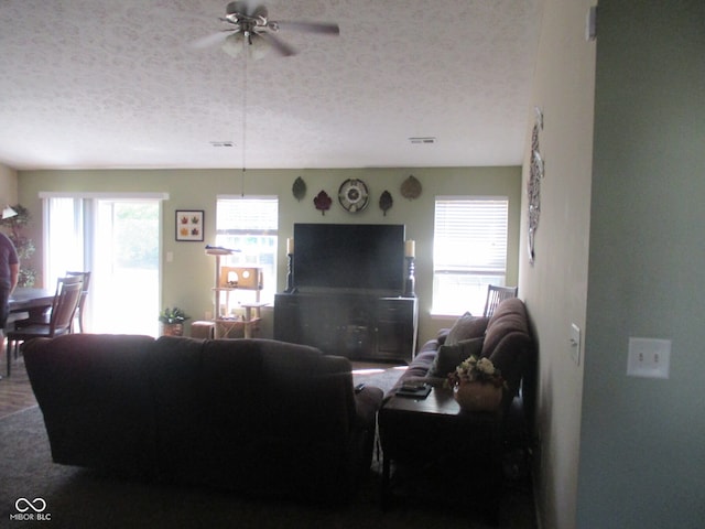 living room with ceiling fan and a textured ceiling