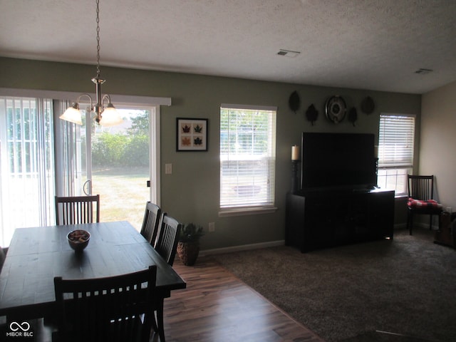 dining room with dark hardwood / wood-style floors, an inviting chandelier, and a textured ceiling