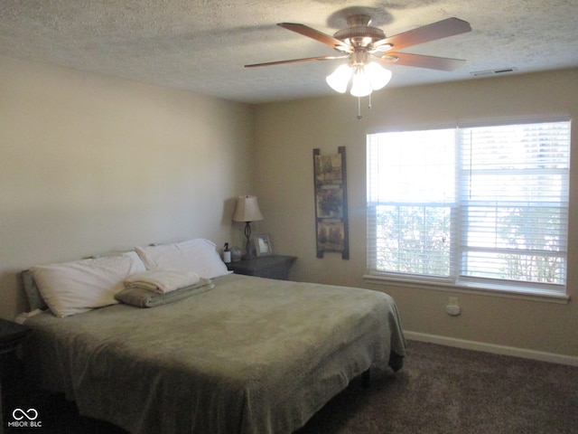 bedroom featuring a textured ceiling, dark carpet, and ceiling fan