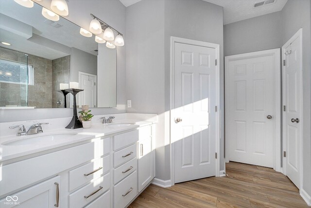 bathroom with vanity, wood-type flooring, and a tile shower