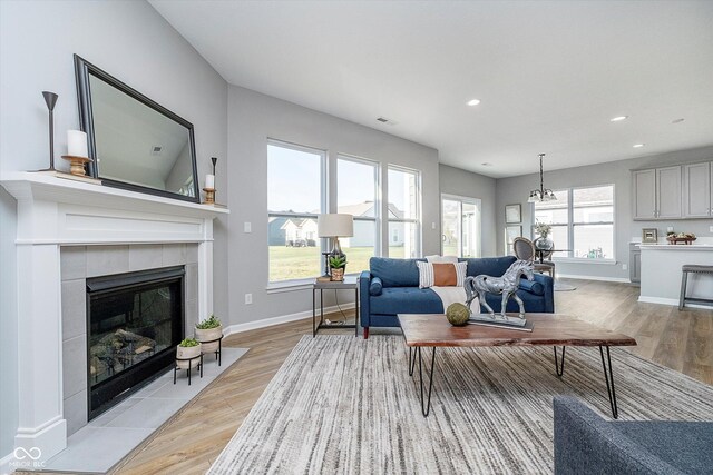 living room featuring a wealth of natural light, a tiled fireplace, and light hardwood / wood-style floors