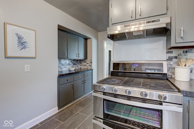 kitchen featuring tasteful backsplash, gray cabinets, dark tile patterned flooring, and stainless steel range oven