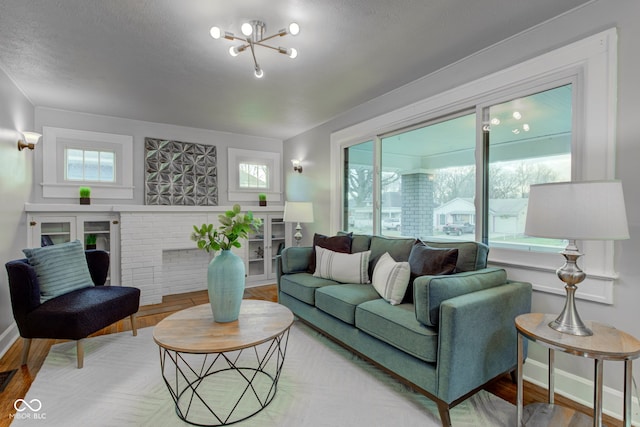 living room with hardwood / wood-style flooring, plenty of natural light, a fireplace, and an inviting chandelier