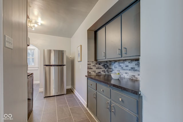 kitchen with gray cabinets, stainless steel fridge, light tile patterned floors, and tasteful backsplash