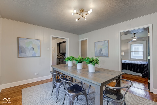 dining space featuring ceiling fan with notable chandelier, a textured ceiling, and hardwood / wood-style flooring