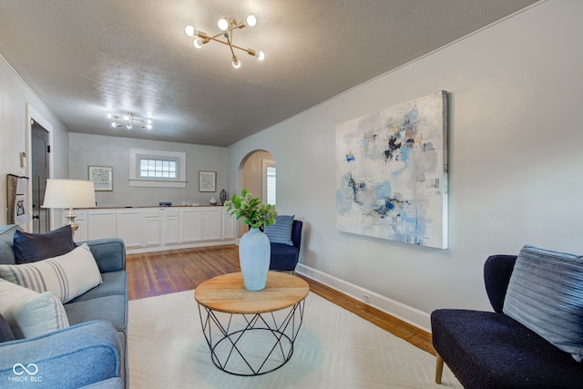 living room with light wood-type flooring, a textured ceiling, and a chandelier