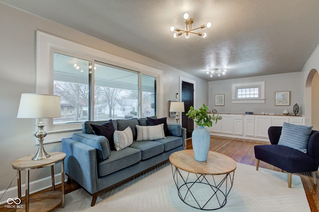 living room with a chandelier, wood-type flooring, and a textured ceiling