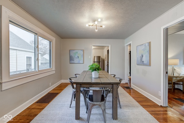 dining room featuring hardwood / wood-style floors, a textured ceiling, and a chandelier