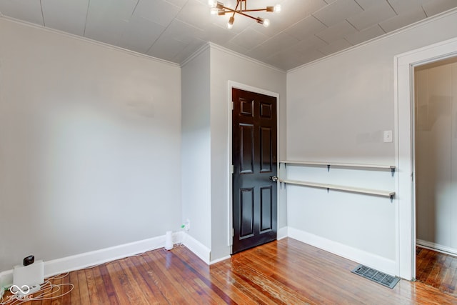 entryway featuring a chandelier, hardwood / wood-style flooring, and crown molding