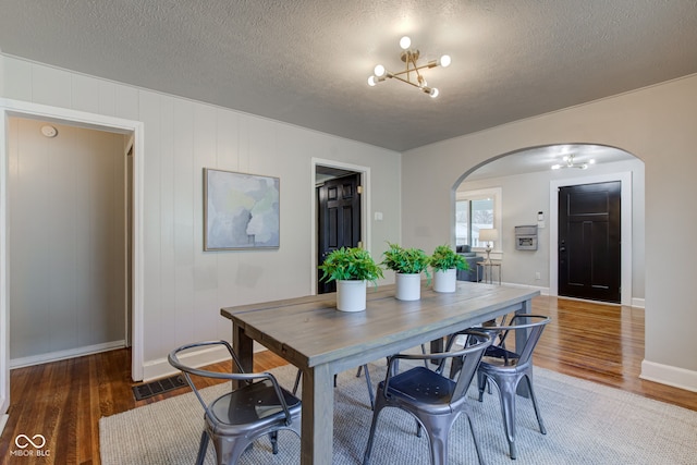 dining space with a chandelier, a textured ceiling, and dark hardwood / wood-style floors