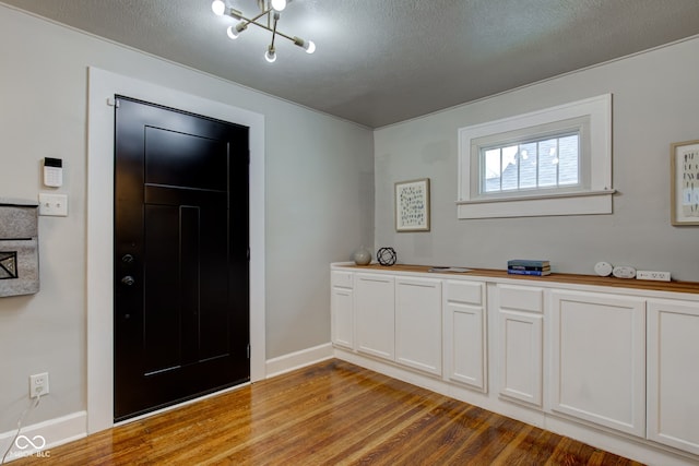 entrance foyer featuring light hardwood / wood-style floors, a textured ceiling, and an inviting chandelier