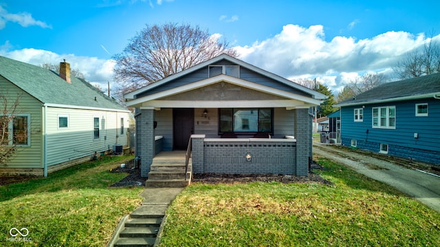 bungalow-style house with central AC unit, covered porch, and a front yard